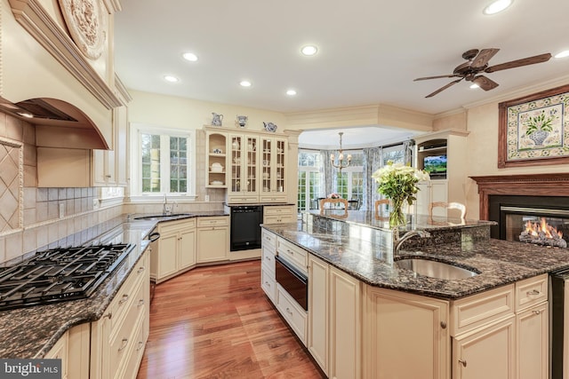 kitchen with decorative light fixtures, sink, dark stone countertops, gas stovetop, and cream cabinetry