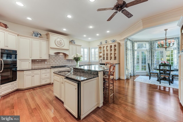 kitchen featuring pendant lighting, a center island with sink, and cream cabinetry