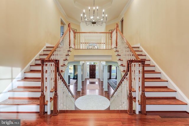 staircase with hardwood / wood-style floors, crown molding, a raised ceiling, and a chandelier