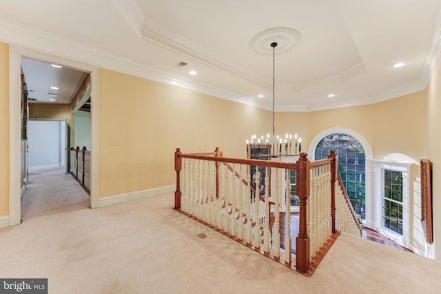 corridor with an inviting chandelier, ornamental molding, a tray ceiling, and carpet