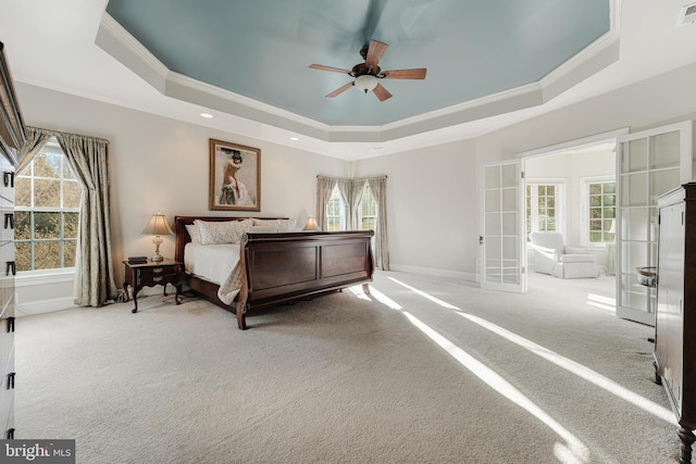 carpeted bedroom with a raised ceiling, ornamental molding, ceiling fan, and french doors