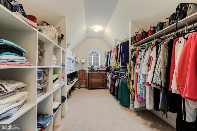 spacious closet with vaulted ceiling and light colored carpet