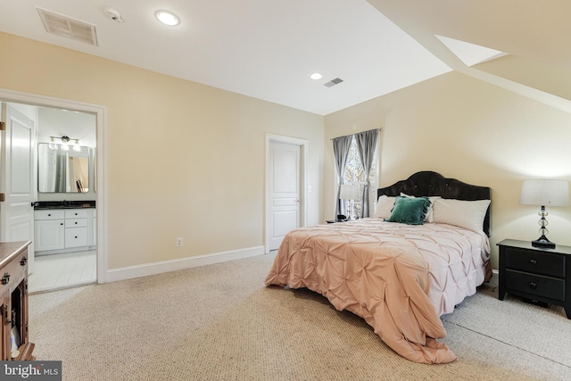 carpeted bedroom with ensuite bath and lofted ceiling