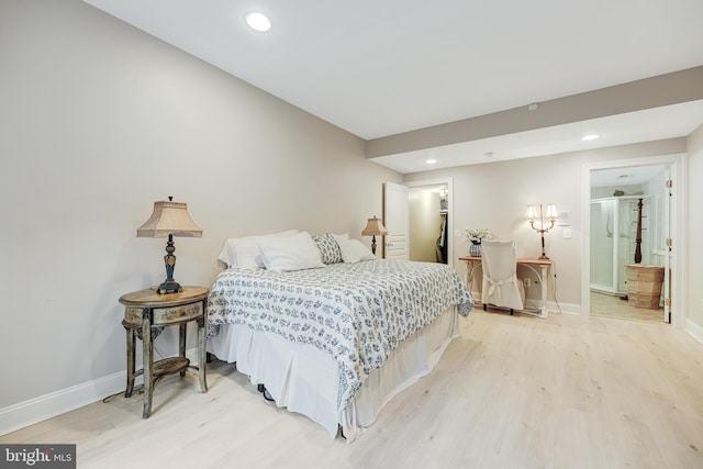 bedroom with connected bathroom and light wood-type flooring