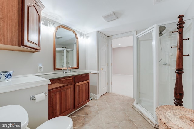 bathroom featuring tile patterned flooring, vanity, a shower with shower door, and toilet