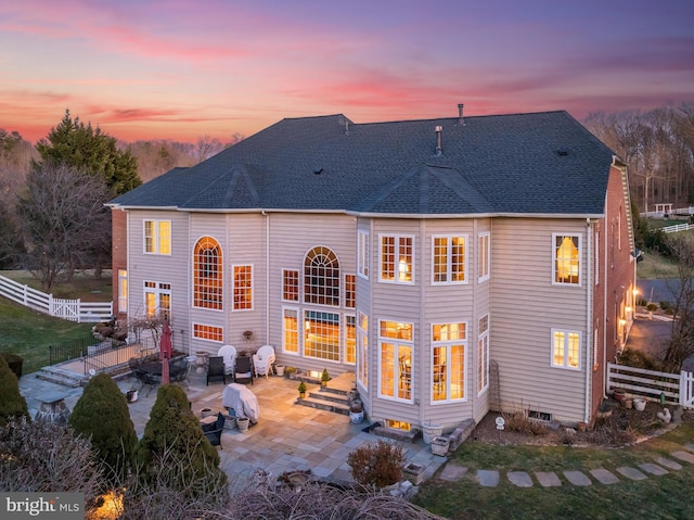 back house at dusk featuring a patio area