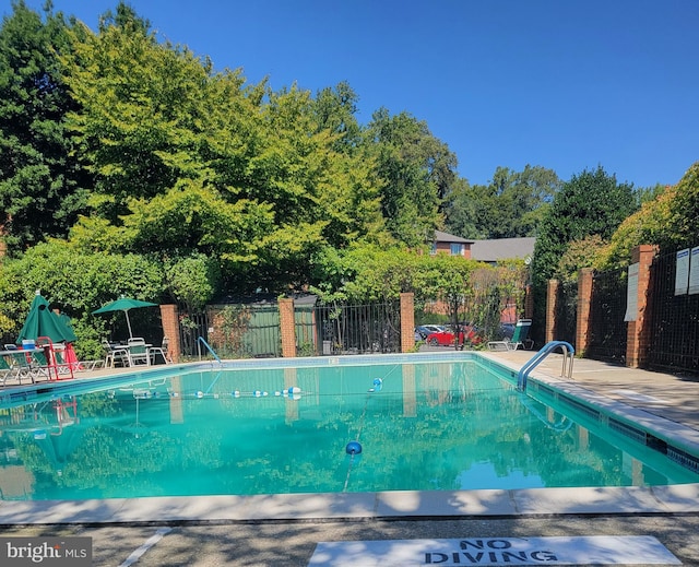 pool with a patio area and fence