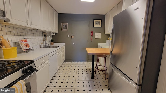 kitchen with stainless steel appliances, light countertops, backsplash, white cabinetry, and a sink