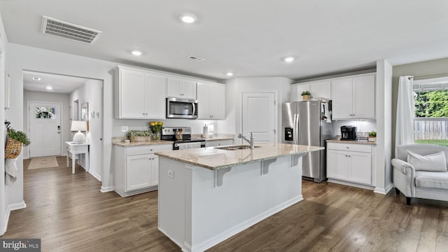 18075 Coolidge Ln, Bowling Green, VA 22427 - kitchen featuring stainless steel appliances, a sink, dark wood finished floors, white cabinetry, and a kitchen bar