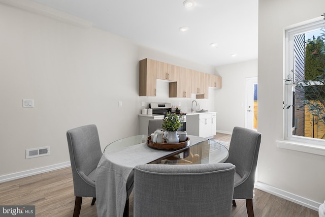 dining area with sink and light wood-type flooring