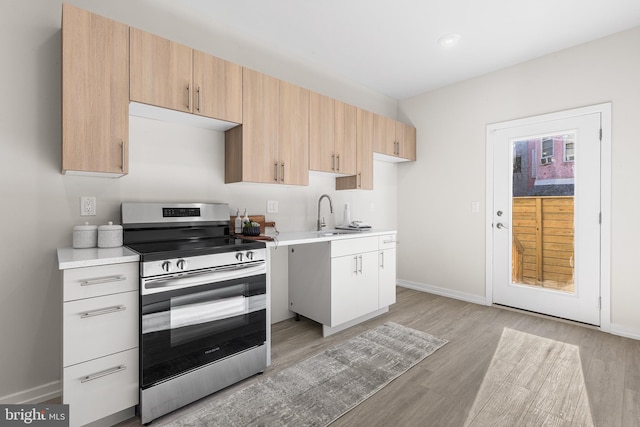 kitchen with stainless steel electric range, light brown cabinetry, sink, white cabinets, and light hardwood / wood-style flooring