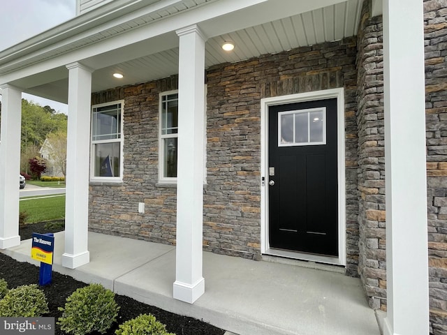 view of exterior entry featuring covered porch and stone siding