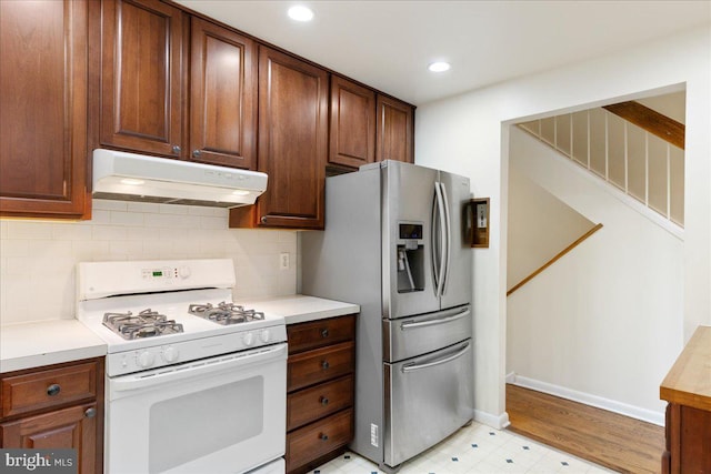 kitchen featuring tasteful backsplash, stainless steel fridge with ice dispenser, and white gas range oven