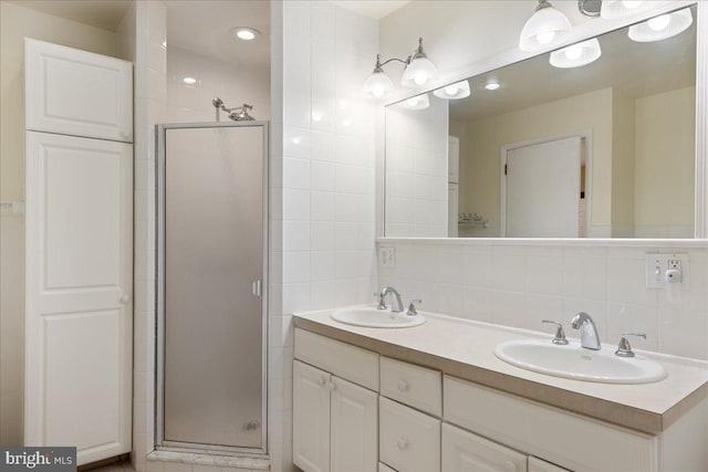 bathroom featuring an enclosed shower, backsplash, vanity, and tile walls