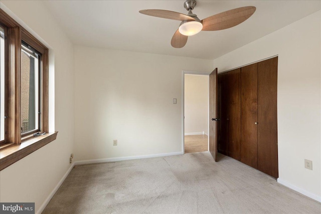 unfurnished bedroom with ceiling fan, light colored carpet, and a closet