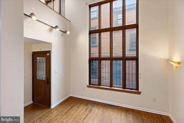 spare room featuring a towering ceiling and hardwood / wood-style flooring