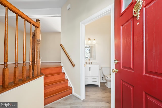 entryway featuring light wood-style flooring, baseboards, and stairs