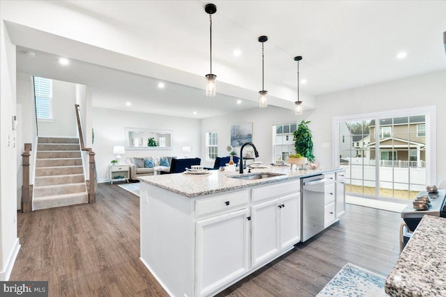 kitchen featuring a sink, white cabinets, open floor plan, dishwasher, and a center island with sink