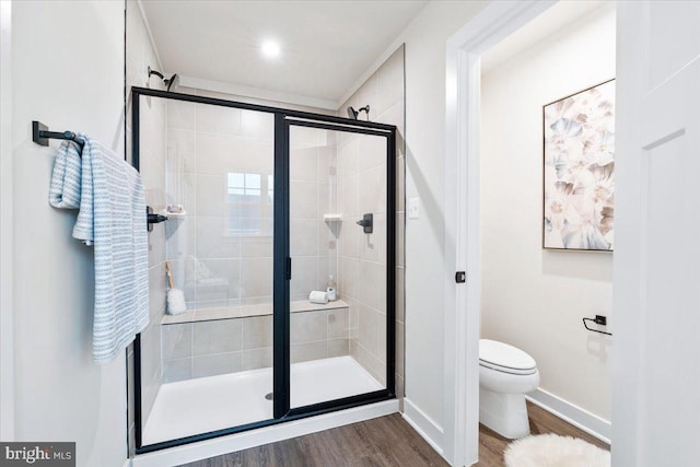 full bathroom featuring toilet, a stall shower, baseboards, and wood finished floors