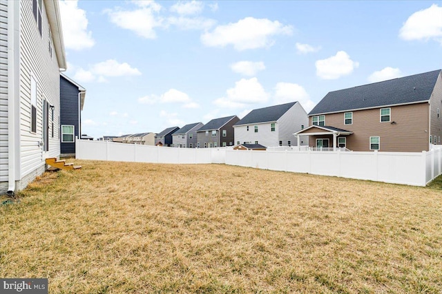 view of yard featuring a residential view, fence, and entry steps