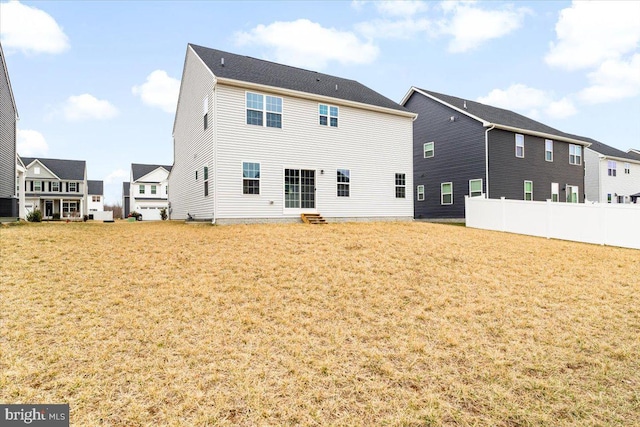 rear view of property with a lawn, entry steps, fence, cooling unit, and a residential view