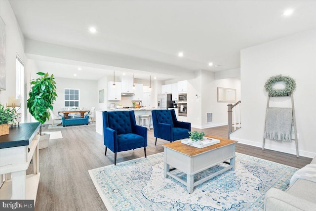 living room featuring stairway, recessed lighting, visible vents, and light wood-style floors