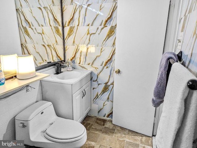 bathroom featuring vanity, toilet, and tile walls