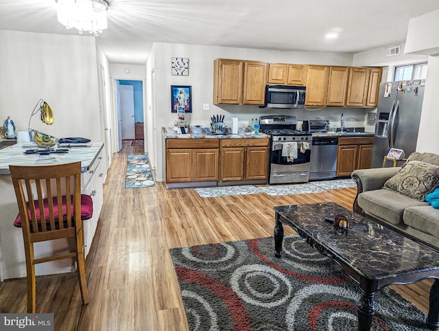 kitchen featuring appliances with stainless steel finishes, sink, an inviting chandelier, and light wood-type flooring