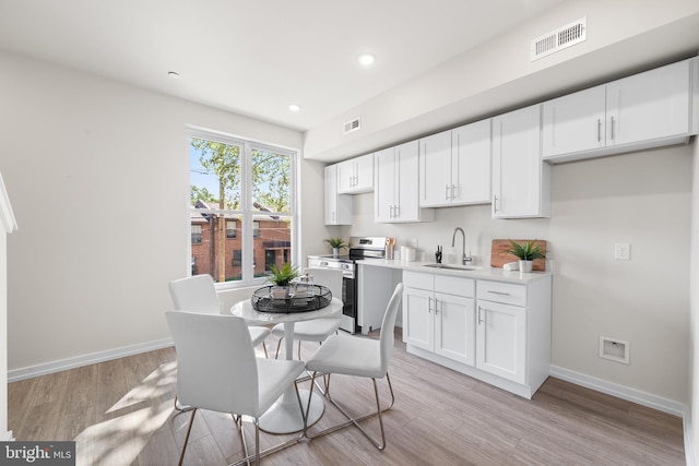 kitchen featuring stainless steel electric range oven, sink, and light hardwood / wood-style flooring