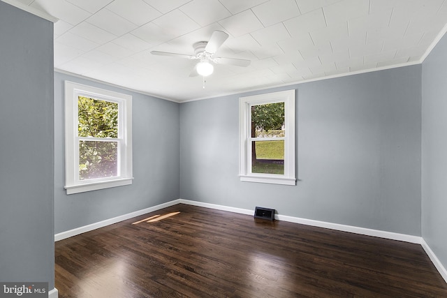 empty room with a healthy amount of sunlight, dark hardwood / wood-style floors, and ornamental molding