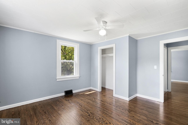 unfurnished bedroom featuring dark wood-type flooring, ceiling fan, crown molding, and a closet