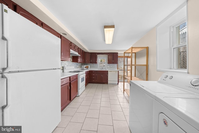 kitchen with sink, white appliances, backsplash, washing machine and dryer, and light tile patterned flooring