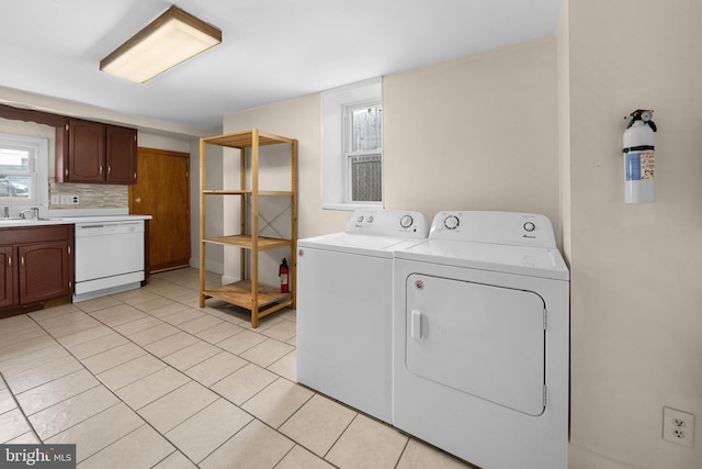 washroom with light tile patterned flooring, washer and clothes dryer, and sink