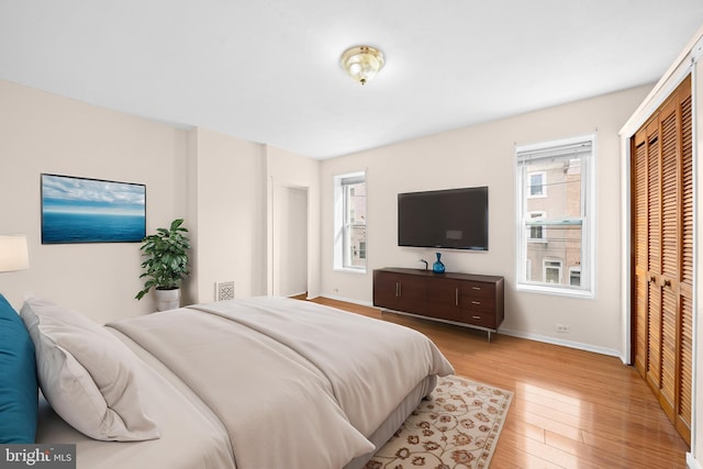 bedroom featuring multiple windows, a closet, and light hardwood / wood-style flooring