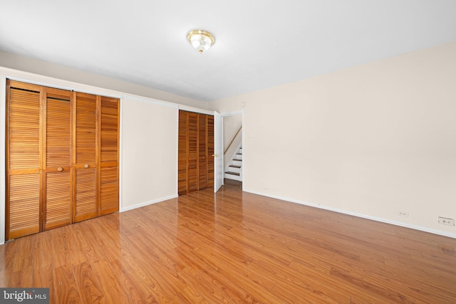 unfurnished bedroom with two closets and light hardwood / wood-style flooring