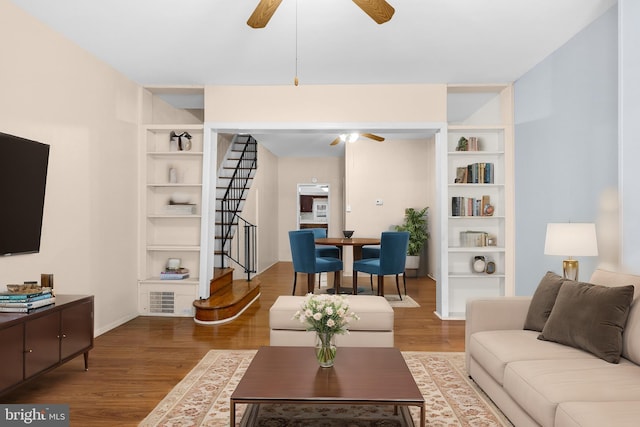 living room featuring hardwood / wood-style flooring, ceiling fan, and built in shelves