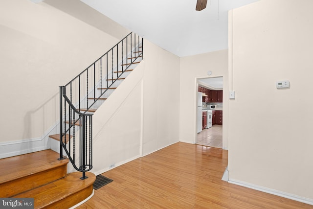 stairs featuring hardwood / wood-style flooring and ceiling fan