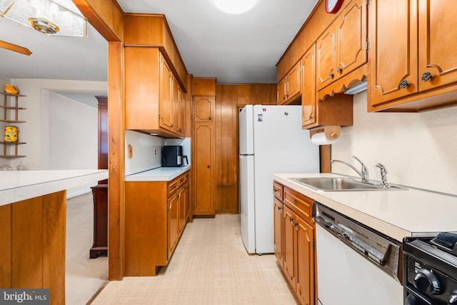 kitchen with black range, dishwasher, sink, and white fridge