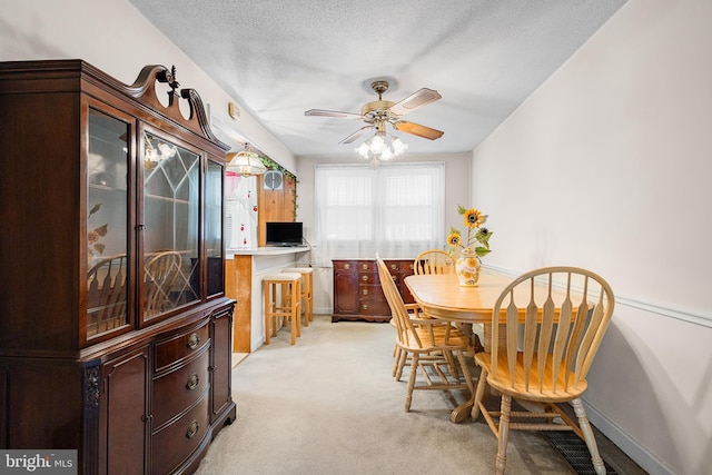 dining area featuring ceiling fan, light colored carpet, and a textured ceiling