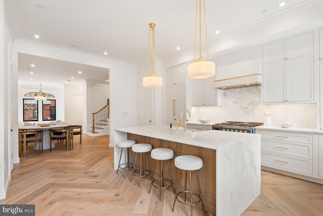 kitchen with tasteful backsplash, a center island with sink, range, crown molding, and white cabinetry