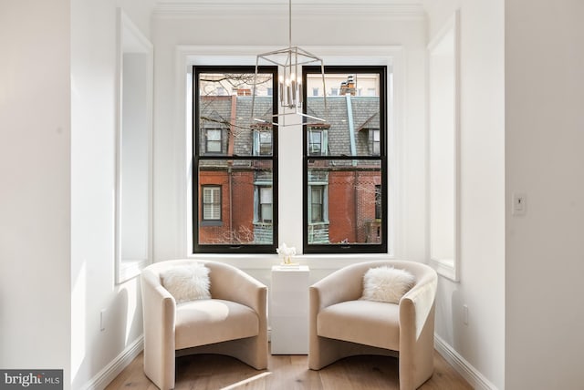 sitting room featuring an inviting chandelier, light wood-style flooring, baseboards, and crown molding