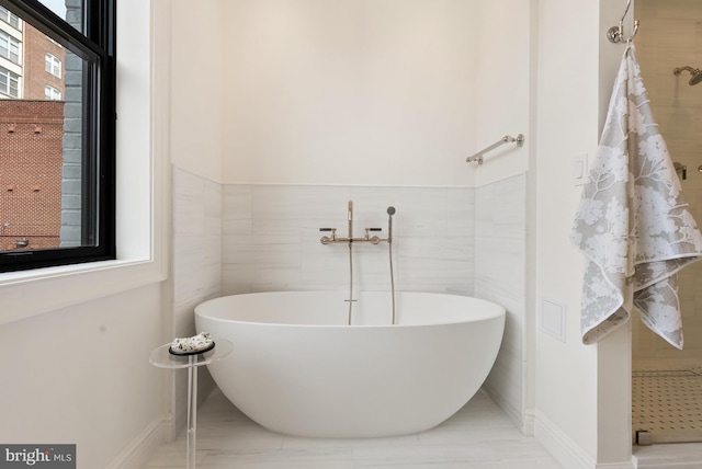 full bath featuring a freestanding tub and tile walls