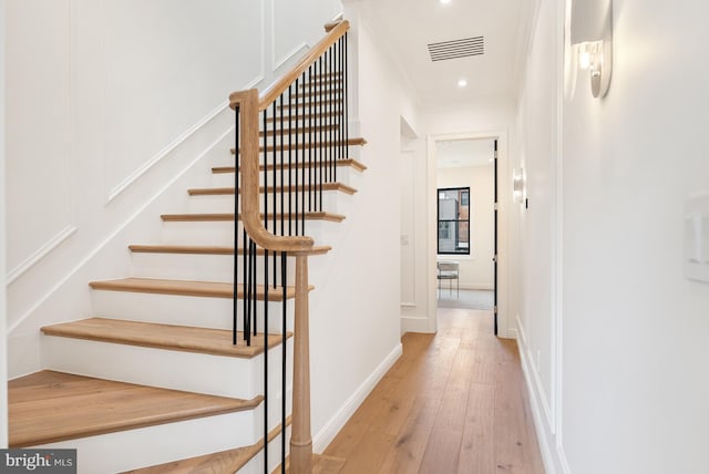 stairs featuring visible vents, baseboards, hardwood / wood-style flooring, ornamental molding, and recessed lighting