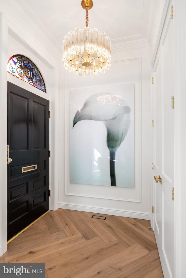 entryway featuring a chandelier and crown molding