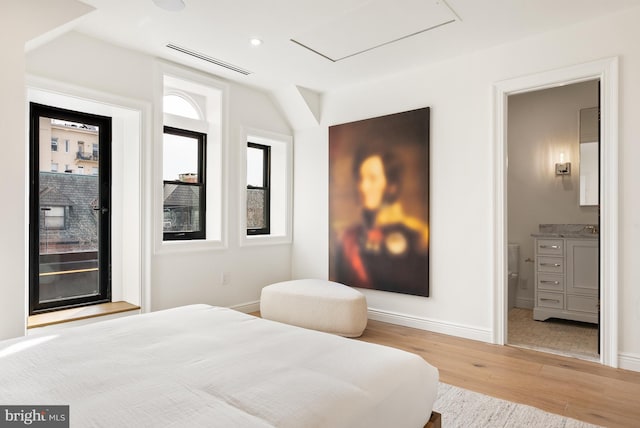 bedroom with baseboards, visible vents, wood finished floors, and ensuite bathroom