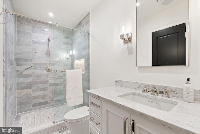 bathroom with toilet, a shower stall, and vanity