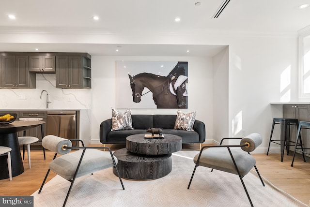 living area featuring light wood-style floors, baseboards, ornamental molding, and recessed lighting