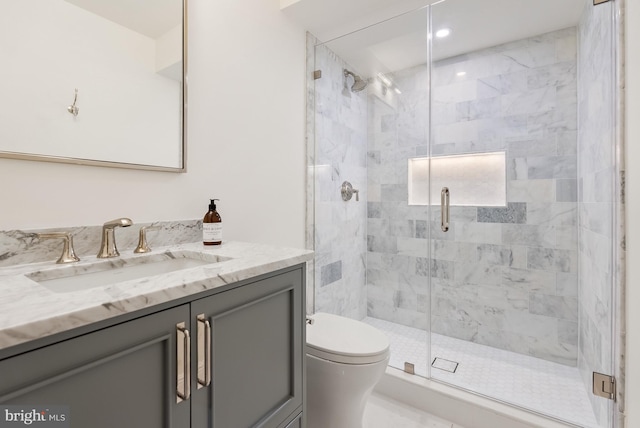 bathroom with a shower stall, toilet, and vanity