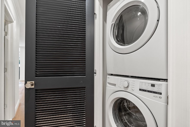 washroom featuring stacked washer and dryer, wood finished floors, and laundry area