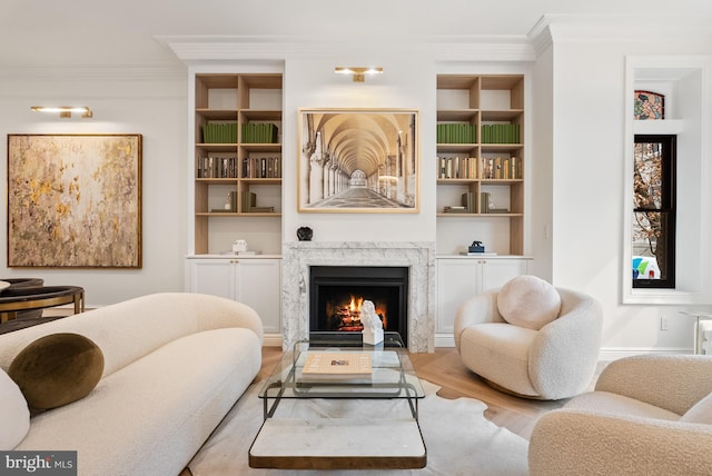 sitting room with built in shelves, crown molding, a high end fireplace, wood finished floors, and baseboards